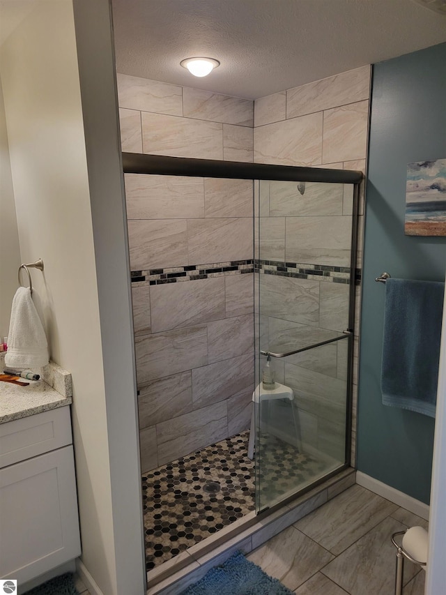 921 Cobalt St Unit 48, Traverse City, MI 49696 - bathroom with a stall shower, baseboards, a textured ceiling, marble finish flooring, and vanity