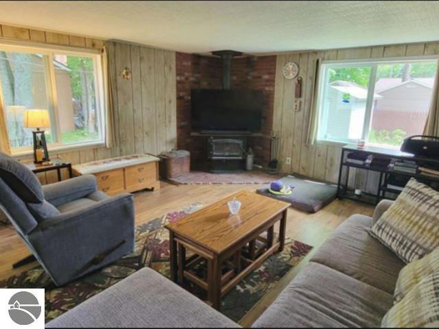13876 Merrill Ave, Kalkaska, MI 49646 - living area with a wood stove, wood finished floors, and wooden walls