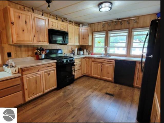 13876 Merrill Ave, Kalkaska, MI 49646 - kitchen with light countertops, wood finished floors, light brown cabinets, a sink, and black appliances