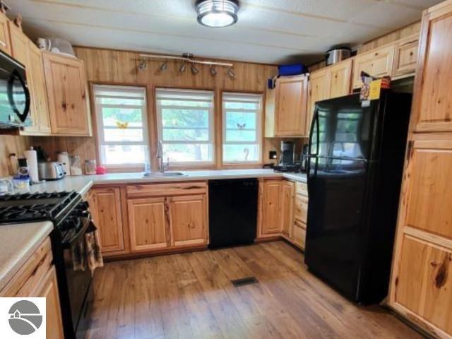 13876 Merrill Ave, Kalkaska, MI 49646 - kitchen featuring light brown cabinetry, light countertops, a sink, light wood-type flooring, and black appliances