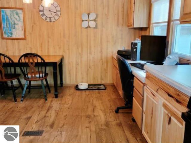 13876 Merrill Ave, Kalkaska, MI 49646 - office space featuring built in desk, light wood-style floors, wooden walls, baseboards, and visible vents