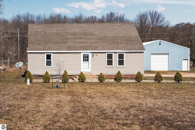 manufactured / mobile home with a detached garage, an outbuilding, a front lawn, and roof with shingles