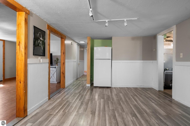 interior space with wainscoting, wood finished floors, and rail lighting