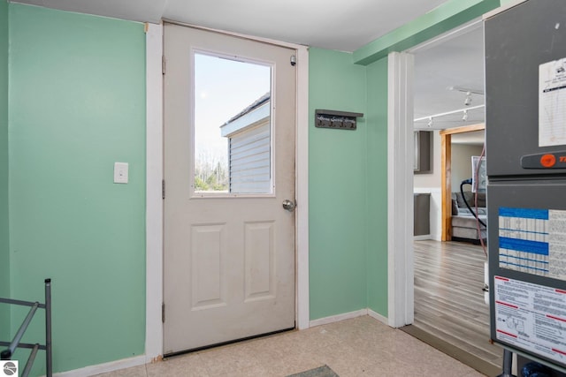 doorway to outside with track lighting and baseboards