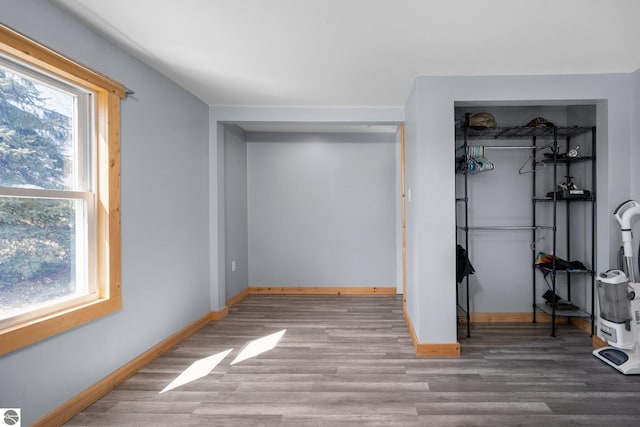 unfurnished bedroom featuring wood finished floors, a closet, and baseboards