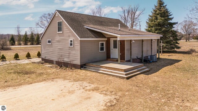 back of property featuring cooling unit and a shingled roof