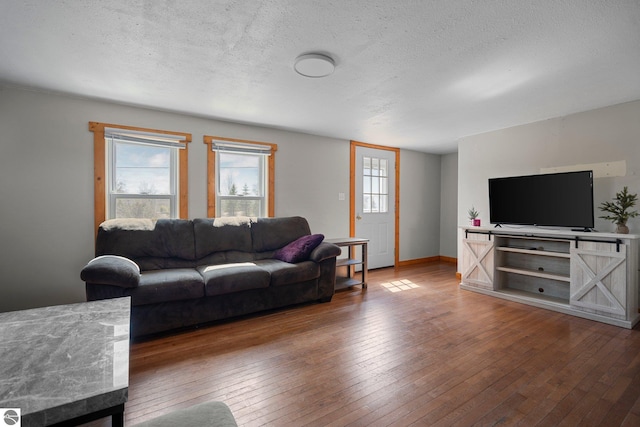 living area featuring wood-type flooring, a textured ceiling, and baseboards