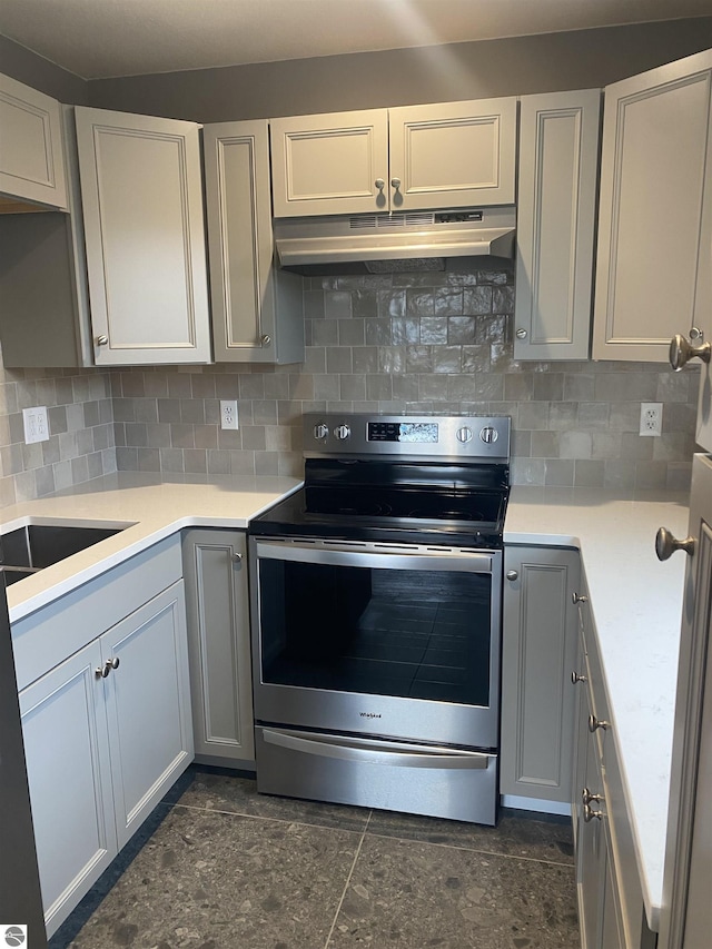 7228B S M-88, Bellaire, MI 49615 - kitchen featuring tasteful backsplash, stainless steel electric stove, light countertops, under cabinet range hood, and gray cabinetry