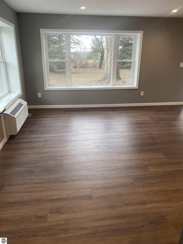 7228B S M-88, Bellaire, MI 49615 - unfurnished room featuring dark wood-style floors, baseboards, a wall mounted AC, and recessed lighting