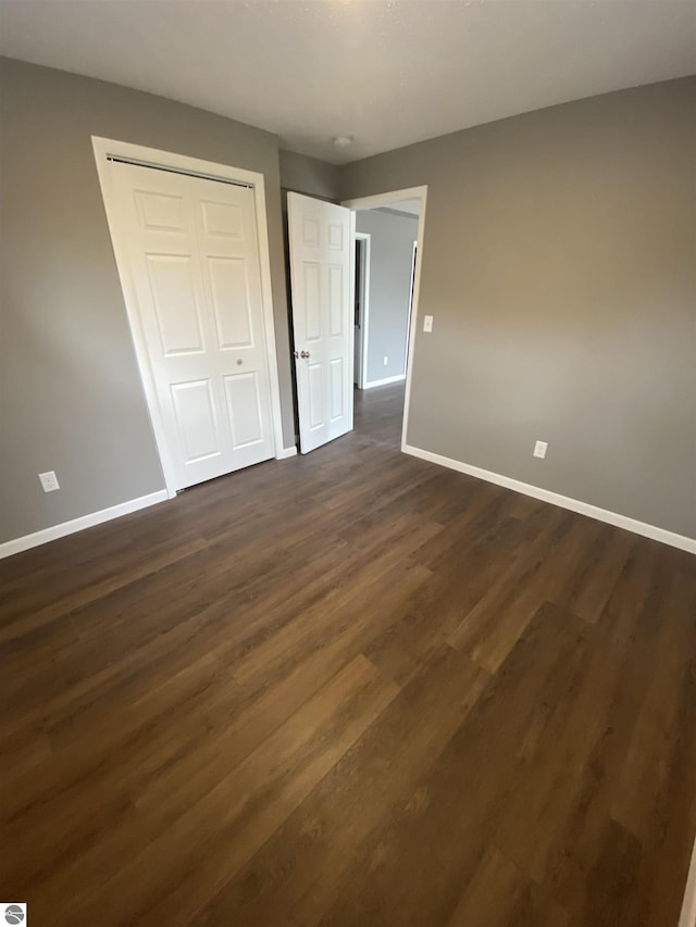 7228B S M-88, Bellaire, MI 49615 - unfurnished bedroom with baseboards, a closet, and dark wood finished floors