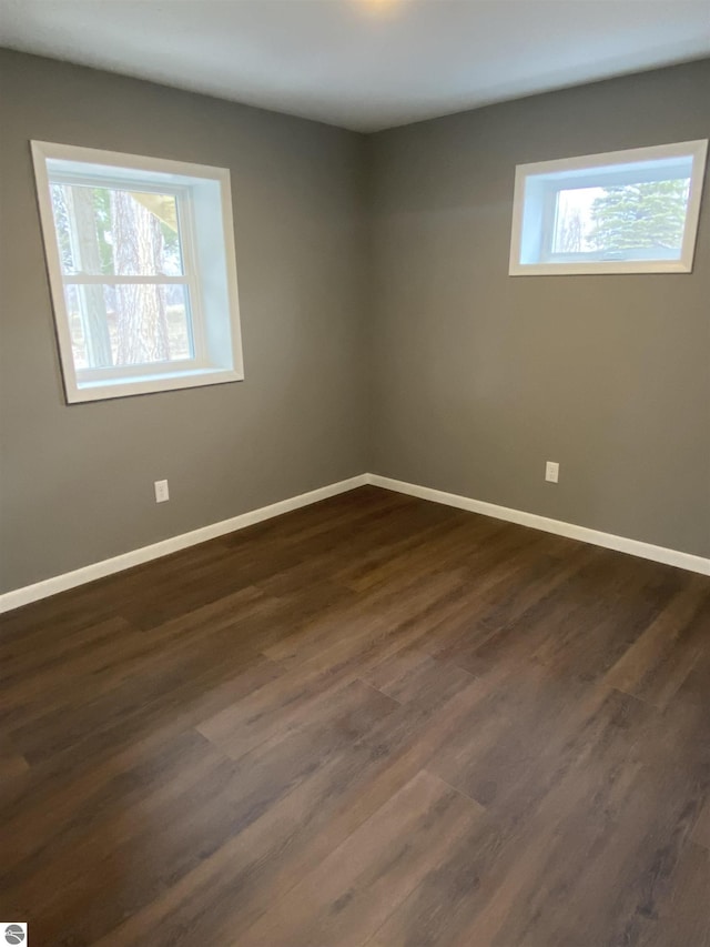 7228B S M-88, Bellaire, MI 49615 - unfurnished room featuring dark wood finished floors, baseboards, and a healthy amount of sunlight