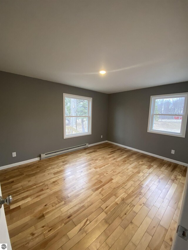 7228B S M-88, Bellaire, MI 49615 - spare room featuring a baseboard heating unit, light wood-style flooring, and baseboards