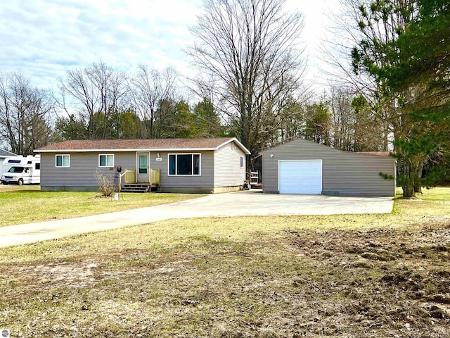 single story home featuring a detached garage, an outbuilding, a front lawn, and driveway
