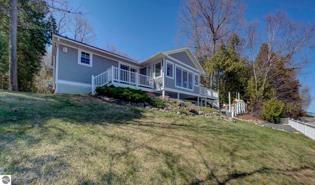rear view of house with a wooden deck, fence, and a yard