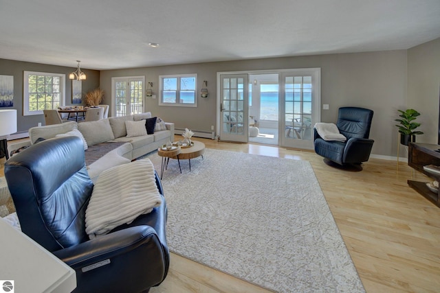 living area with baseboard heating, a healthy amount of sunlight, and wood finished floors