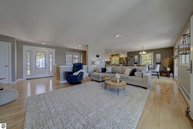 living room featuring light wood-type flooring, an inviting chandelier, recessed lighting, and a baseboard radiator