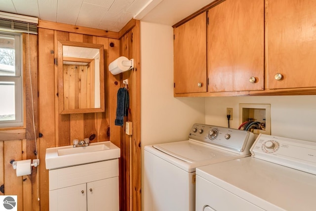 7726 Anway Dr, Battle Creek, MI 49014 - clothes washing area with washing machine and dryer, wooden walls, a sink, and cabinet space