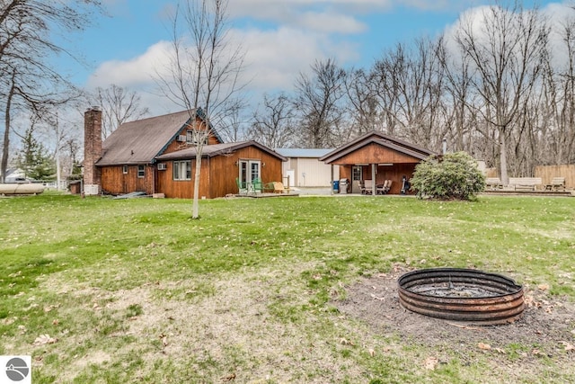 7726 Anway Dr, Battle Creek, MI 49014 - back of house with a yard, a fire pit, and a chimney