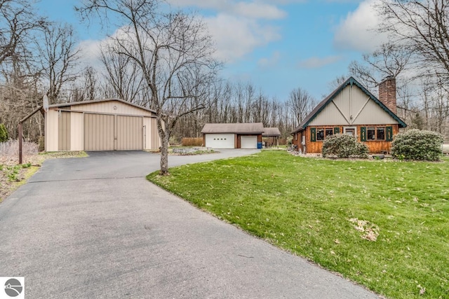 7726 Anway Dr, Battle Creek, MI 49014 - view of front of property with a detached garage, a front lawn, a chimney, and an outbuilding
