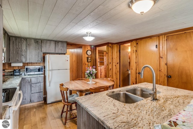 7726 Anway Dr, Battle Creek, MI 49014 - kitchen with a sink, light wood-type flooring, white appliances, wooden walls, and light stone counters