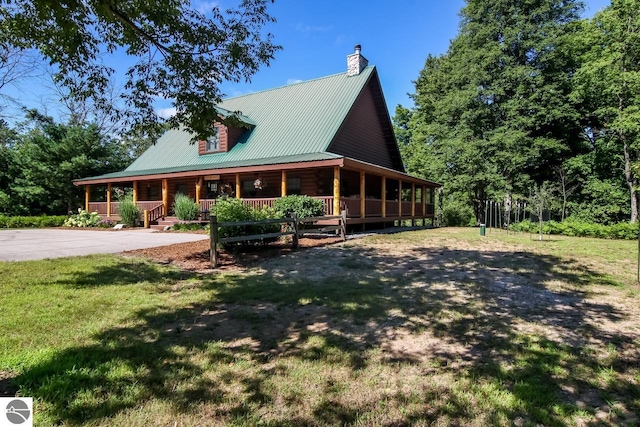 farmhouse-style home featuring a front lawn, a porch, a chimney, metal roof, and log exterior