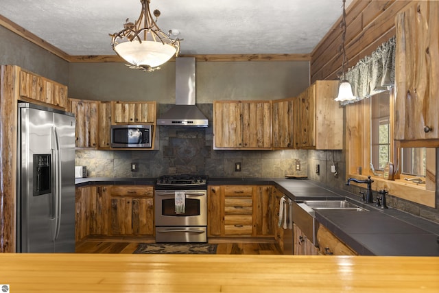 kitchen featuring brown cabinets, dark countertops, wall chimney range hood, and stainless steel appliances