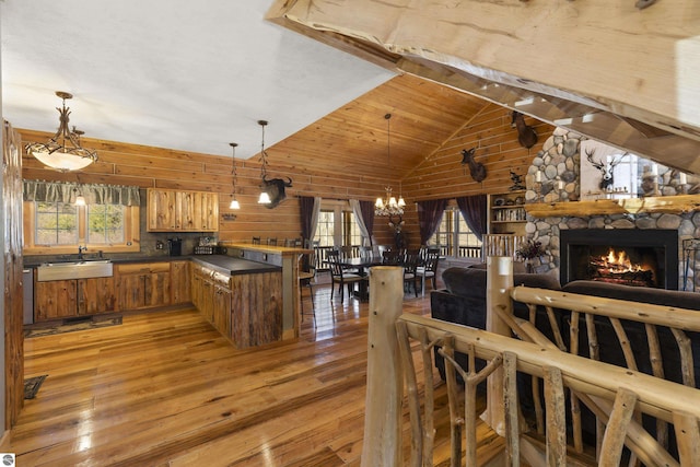 dining room featuring an inviting chandelier, a stone fireplace, wooden ceiling, light wood-style floors, and beam ceiling