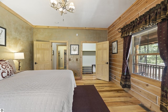 bedroom featuring wood walls, a chandelier, visible vents, and light wood-type flooring