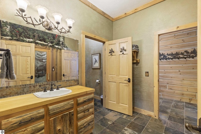 bathroom with baseboards, stone finish flooring, a textured wall, vanity, and ornamental molding