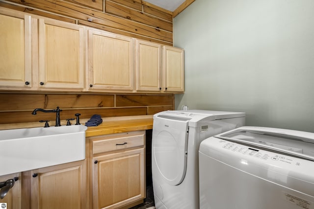 washroom featuring cabinet space, washing machine and clothes dryer, and a sink