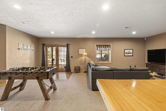 recreation room with a textured ceiling, french doors, light colored carpet, visible vents, and recessed lighting