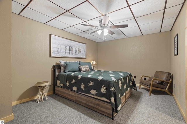 bedroom featuring carpet, a drop ceiling, baseboards, and a ceiling fan