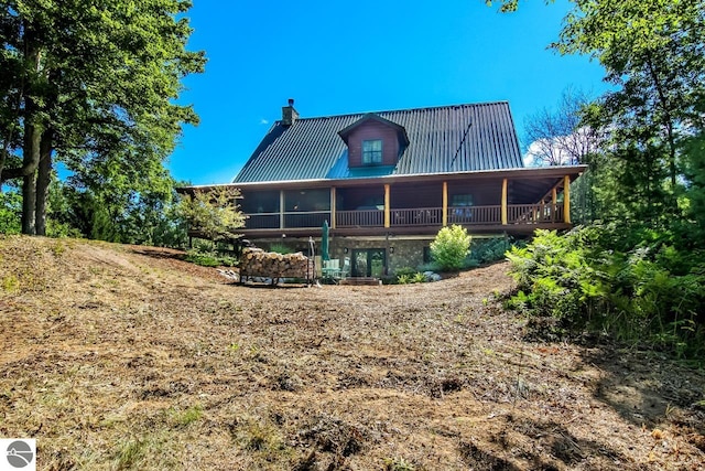 rear view of house featuring a chimney and metal roof