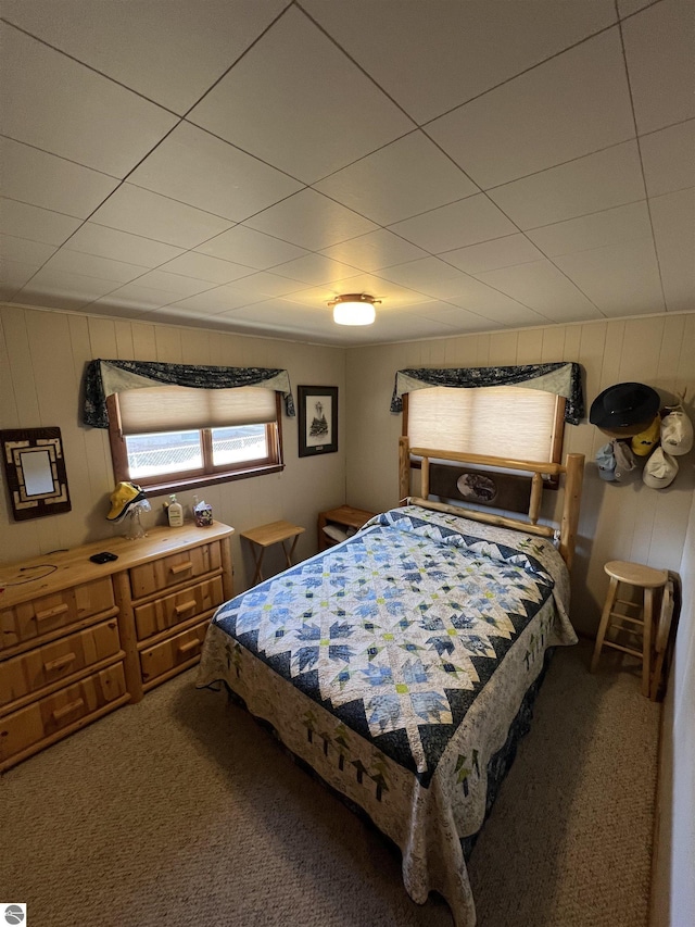 bedroom with carpet flooring and wooden walls