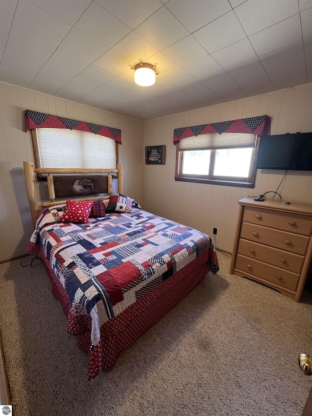 carpeted bedroom featuring wooden walls