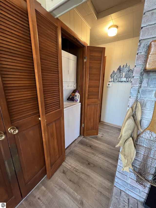laundry room featuring light wood finished floors, stacked washer and dryer, and laundry area