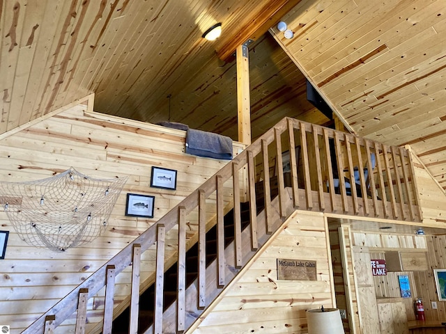 stairway featuring lofted ceiling, wooden ceiling, and wood walls