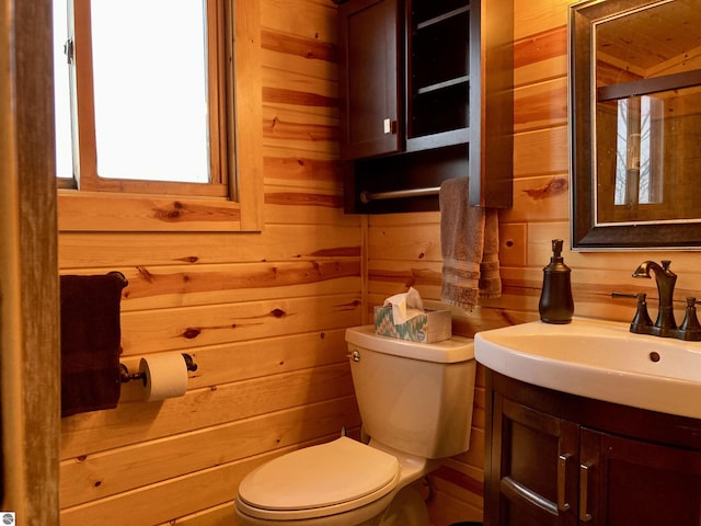 bathroom with wood walls, toilet, and vanity
