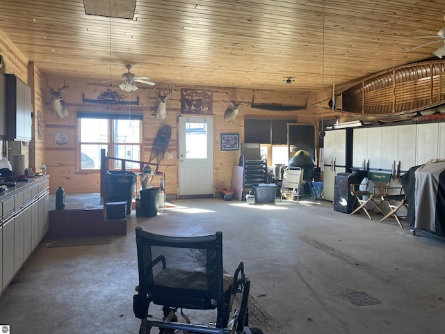 garage with wood ceiling, a ceiling fan, and wood walls