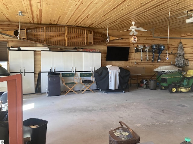 garage with a ceiling fan and wood walls