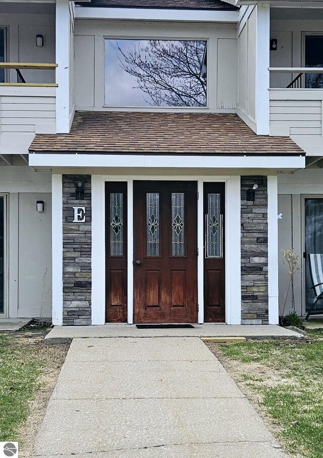 100 Fourth Ave Unit E-3, Tawas City, MI 48763 - view of exterior entry featuring roof with shingles and stone siding