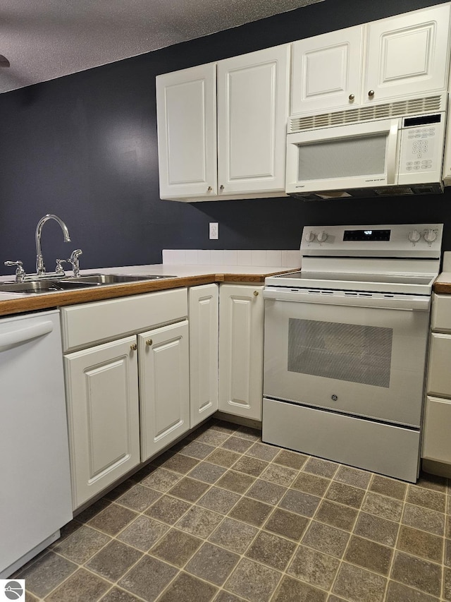 100 Fourth Ave Unit E-3, Tawas City, MI 48763 - kitchen with white cabinets, white appliances, a sink, and a textured ceiling