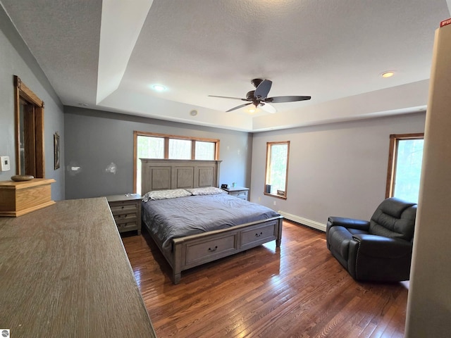 bedroom featuring a baseboard radiator, ceiling fan, a tray ceiling, baseboards, and dark wood-type flooring