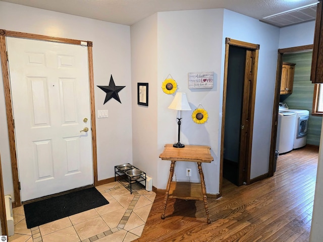 entryway featuring light wood finished floors, baseboards, visible vents, and washer and dryer