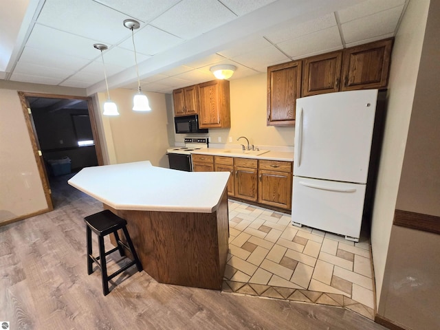 kitchen with a sink, electric range, freestanding refrigerator, black microwave, and light countertops