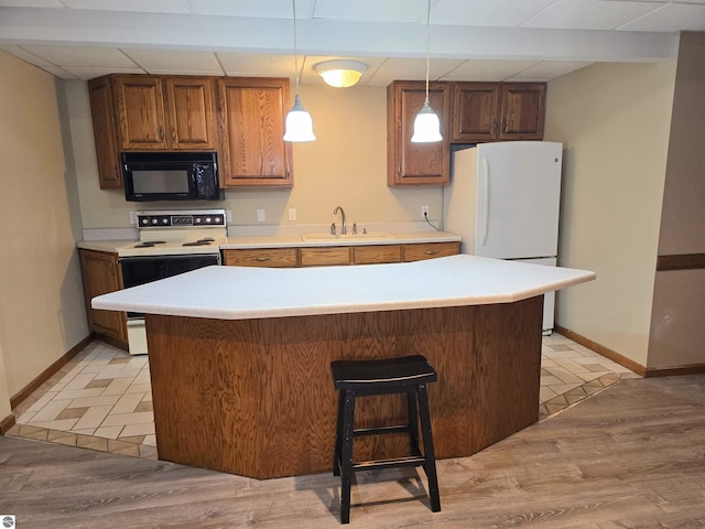 kitchen featuring baseboards, a sink, white appliances, and light countertops