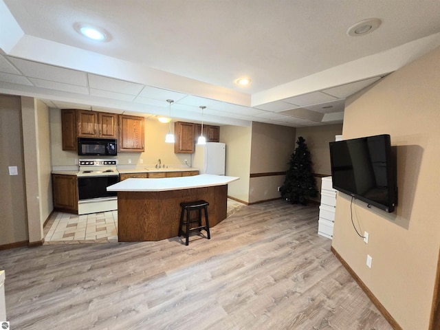 kitchen with light wood finished floors, baseboards, white appliances, light countertops, and a kitchen island