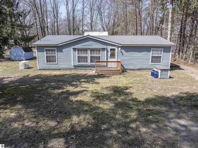view of front of house featuring a front lawn, a storage shed, and metal roof