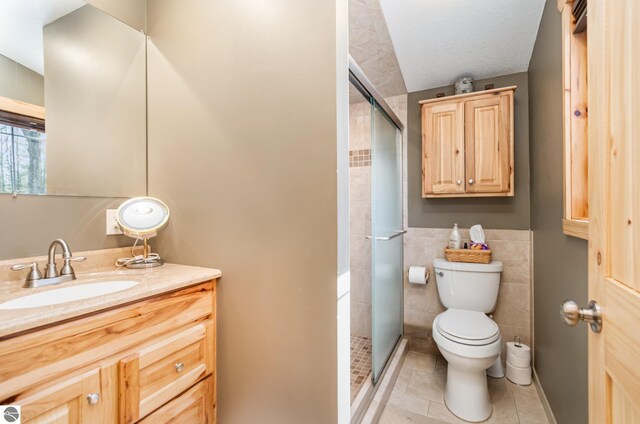3901 W Thendara Dr, Gladwin, MI 48624 - bathroom with tile patterned floors, toilet, vanity, tile walls, and a stall shower