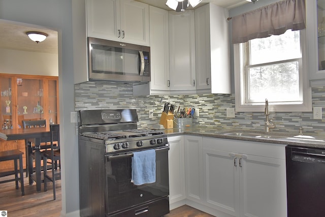 kitchen with black appliances, backsplash, a sink, and white cabinets